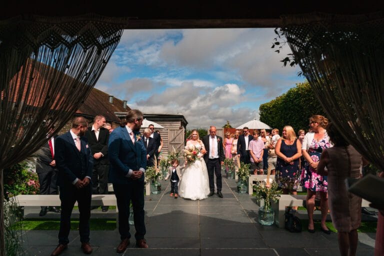 bride-walking-into-outdoor-wedding-ceremony-in-chichester